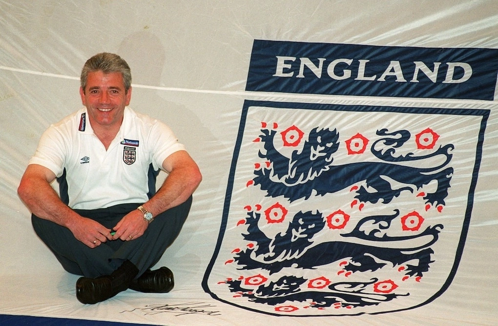 HLV Kevin Keegan tạo dáng bên chiếc áo đấu khổng lồ của tuyển Anh trong buổi công bố danh sách đội tuyển tại khách sạn Metropole ngày 15/5/2000. Chiếc áo này sau đó được sử dụng để cổ động viên Anh trưng bày trên khán đài. Ảnh: Reuters