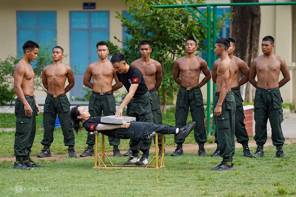 Lê Thị Hoài Thu trong tập luyện nằm trên hai thanh đao và chịu đựng lực từ phiến đá nặng khoảng 50kg. Ảnh: Nguyễn Đông