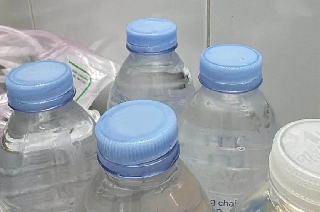 Chai nước không còn nguyên vẹn tem và nhãn được mua tại cửa hàng trước cổng Bệnh viện Hữu nghị Đa khoa Nghệ An. Ảnh: Hùng Lê