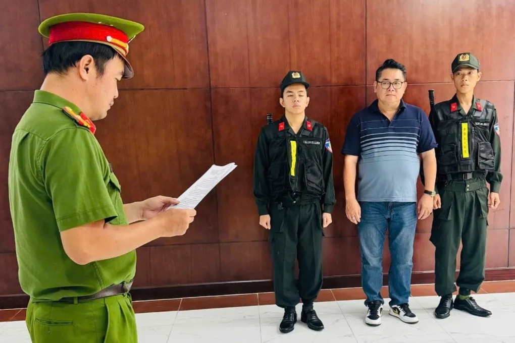 Nguyễn Thành Hiệp (áo thun) nghe cảnh sát đọc lệnh khởi tố. Ảnh: Công an cung cấp