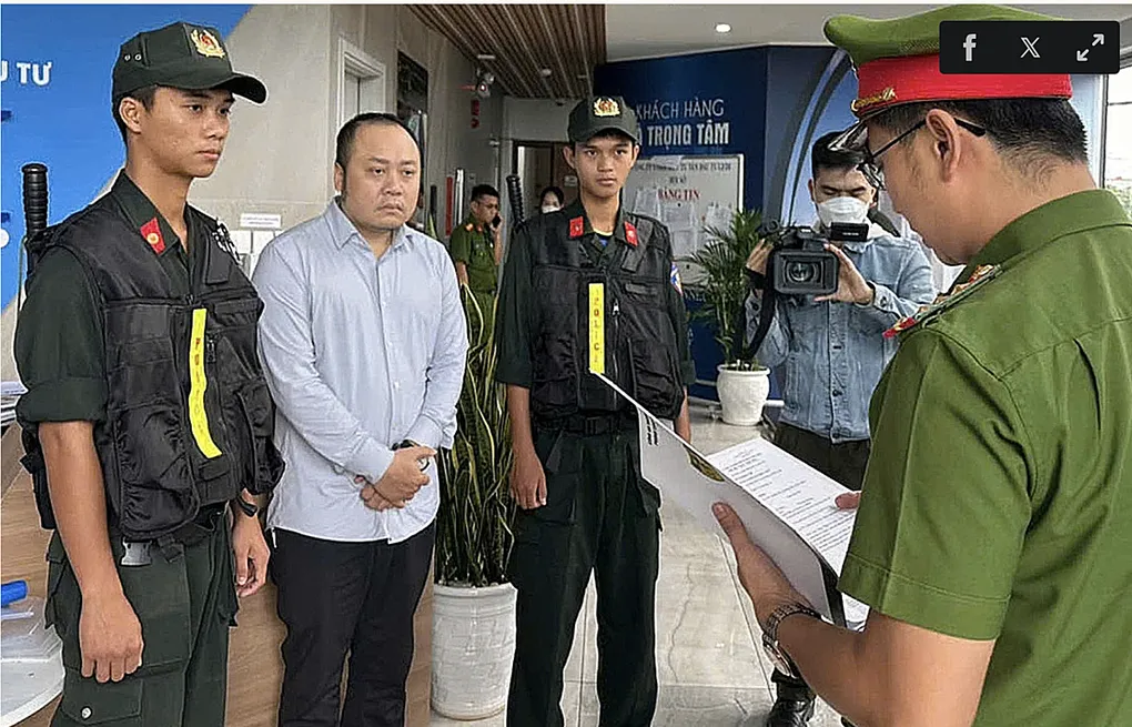 Nguyễn Quang Hoàng nghe đọc lệnh khám xét nơi ở, ngày 8/11. Ảnh:Công an cung cấp