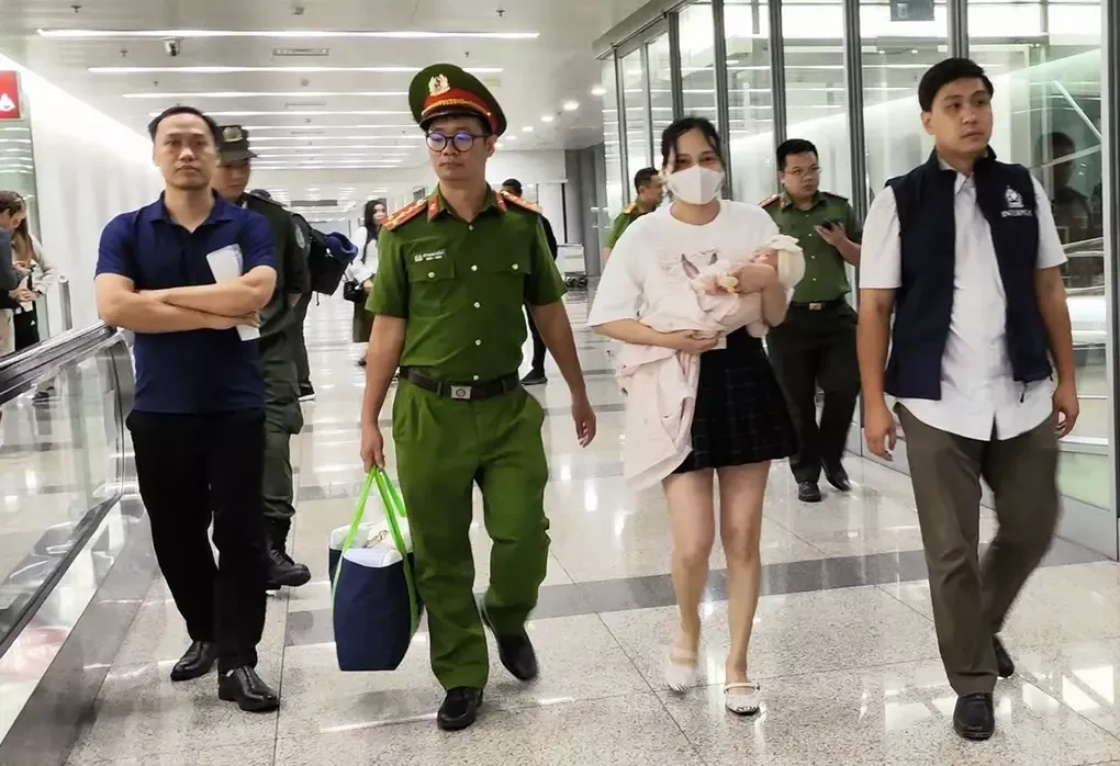 Ngô Thị Thêu bế con nhỏ bị dẫn giải về nước hôm 15/8/2025. Ảnh: Bộ Công an