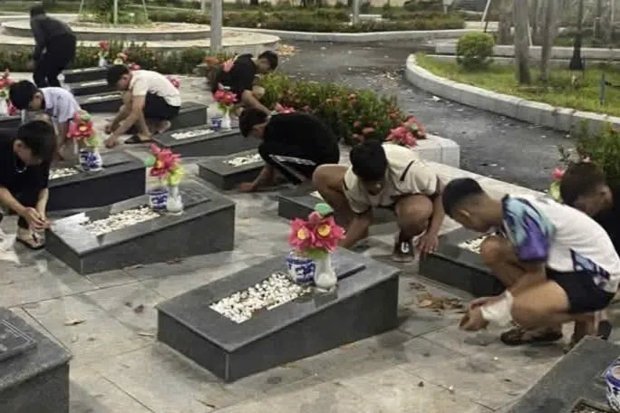 Nhóm thiếu niên quét lá, nhổ cỏ, vệ sinh khuôn viên nghĩa trang liệt sĩ. Ảnh: Công an xã Phú Giáo