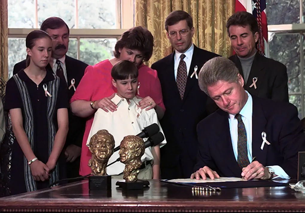 Vợ chồng Maureen - Richard Kanka cùng con gái Jessica và con trai Jeremy chứng kiến Tổng thống Bill Clinton ký ban hành Đạo luật Megan năm 1996. Ảnh: KRT