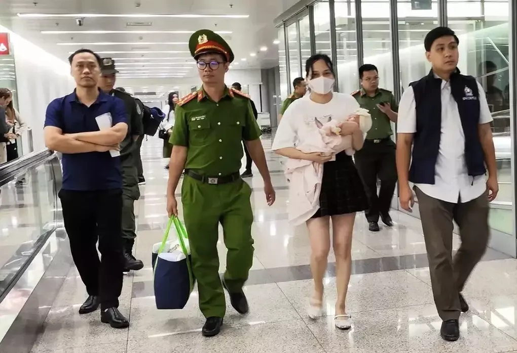 Ngô Thị Thêu bế con nhỏ bị dẫn giải về nước hôm 15/8/2025. Ảnh:Bộ Công an