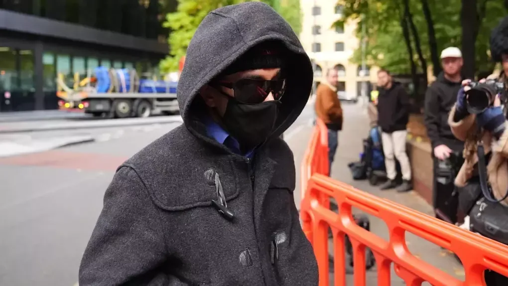 Kashim Chowdhury đeo kính râm tối màu, đội mũ, mặc áo hoodie và đeo găng tay khi đến tòa. Ảnh: BBC